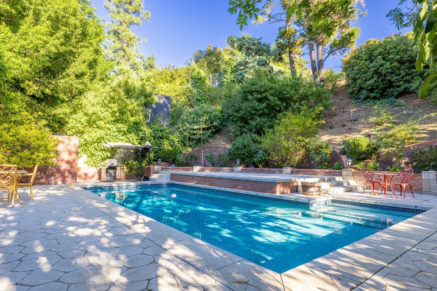 backyard of a luxury studio city pool home with a hill and lush greenery surrounding the pool deck